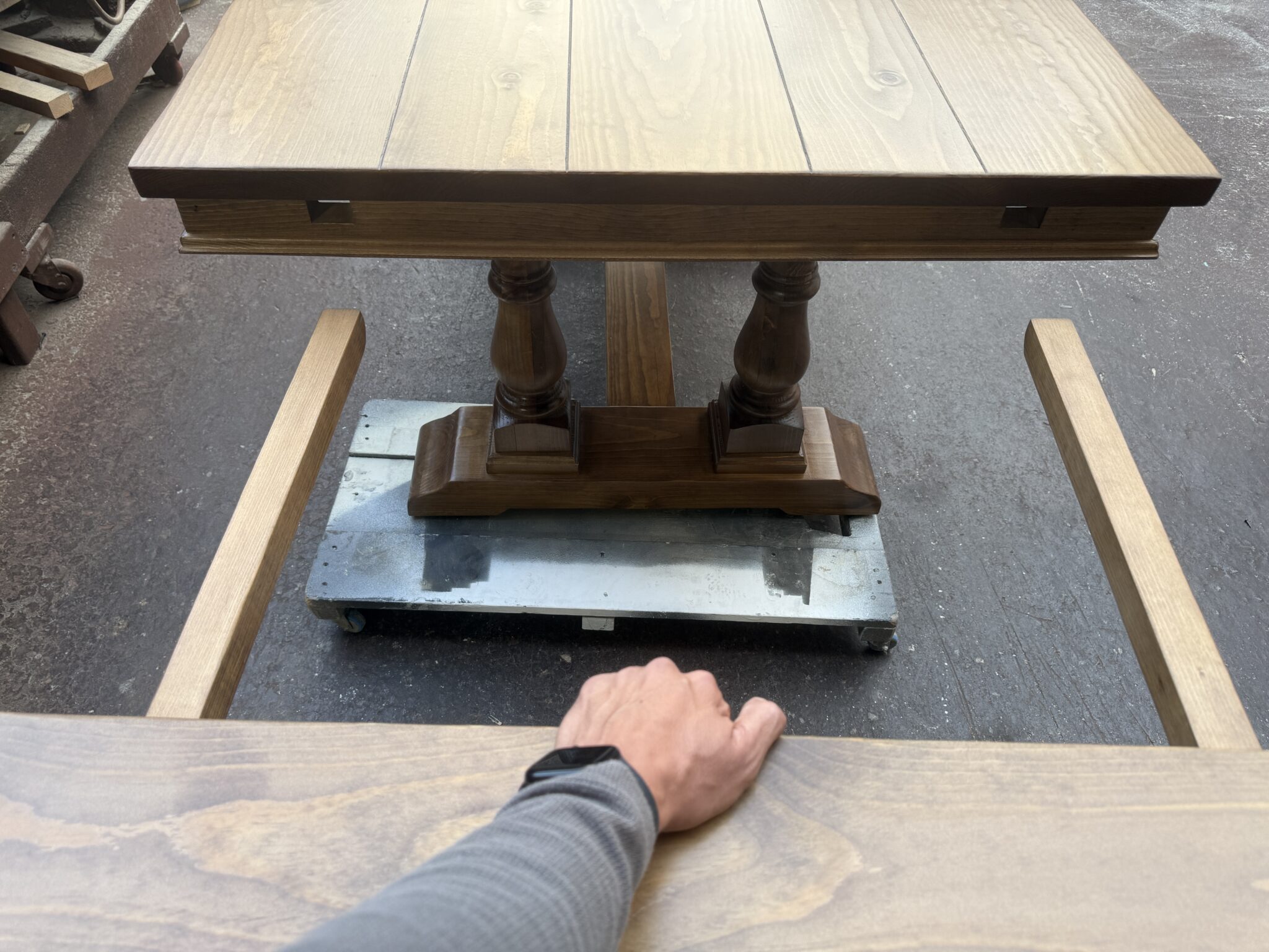 Person holding a breadboard extension with its two support arms aligned toward the table openings