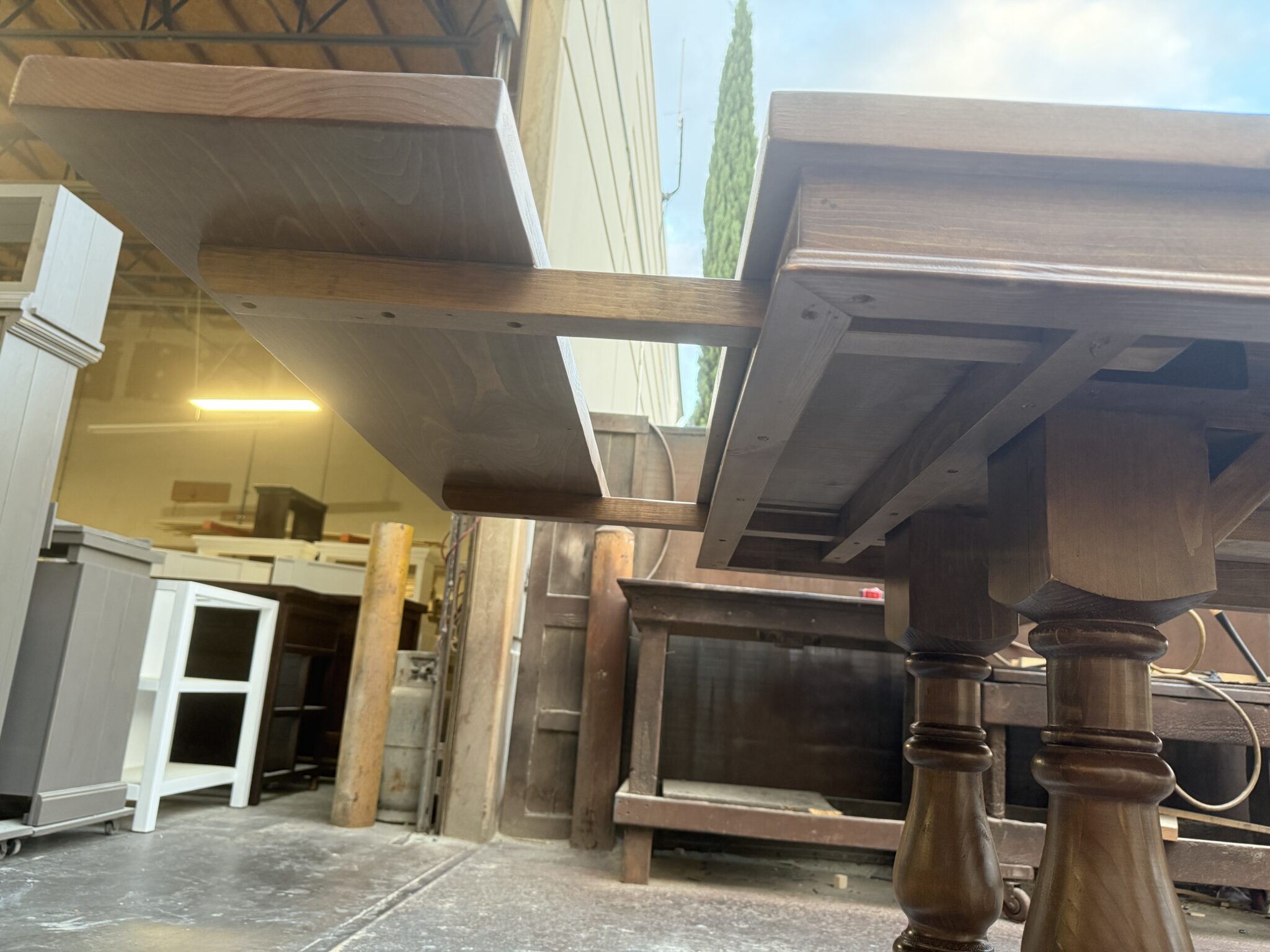 Underside view of a partially inserted extension with wooden arms passing into the table
